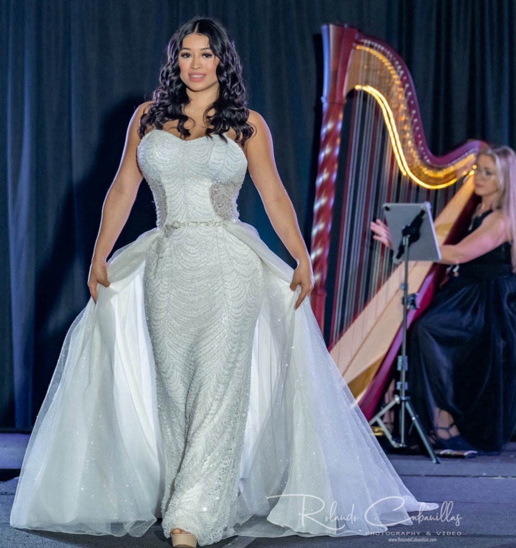 Caroline in a bridal gown on the runway with live harpist